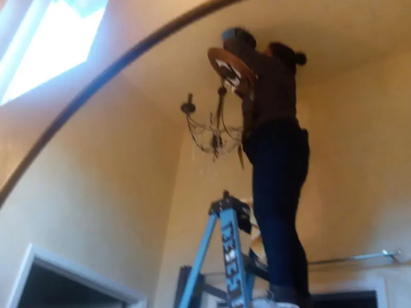 Electrician installing a chandelier in a Chenango residence